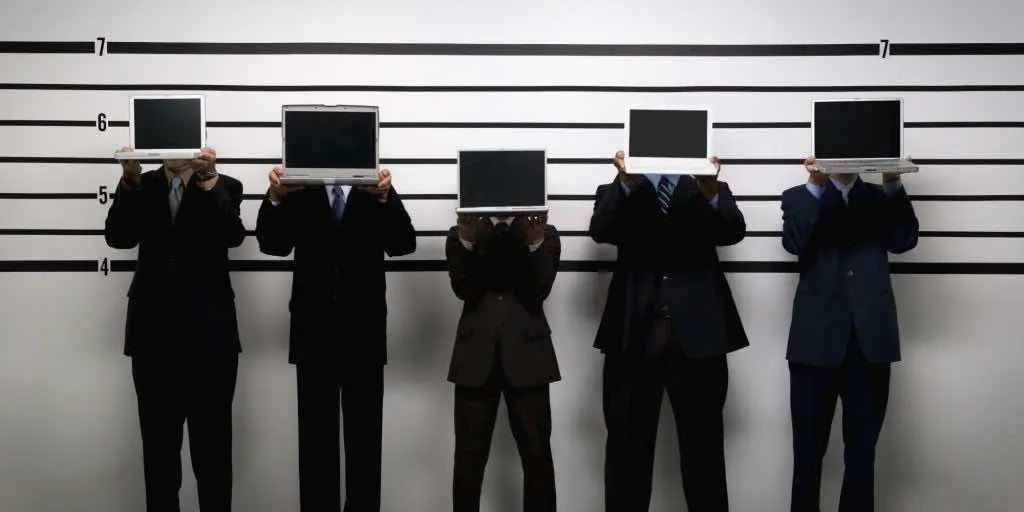 Multi-ethnic businessmen holding laptops in police line up